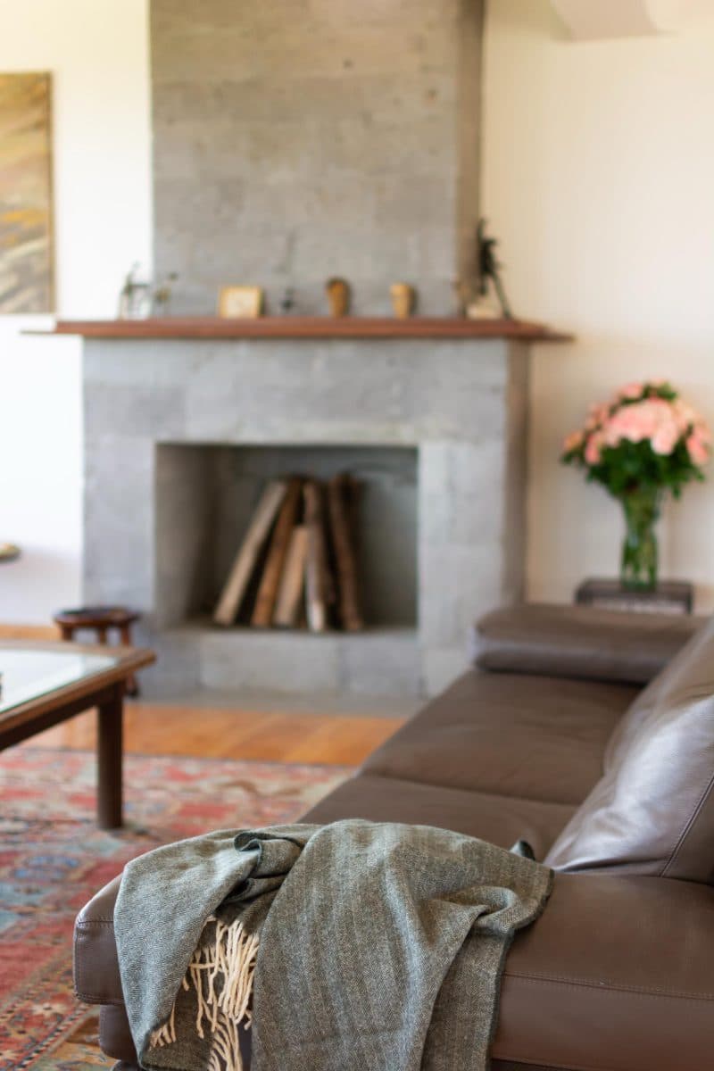 La Maison Bleue Naivasha — stone fireplace with leather sofa and grey throw