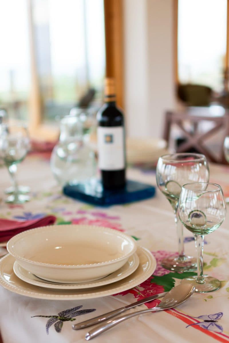La Maison Bleue Naivasha — red wine bottle and glasses on a floral tablecloth