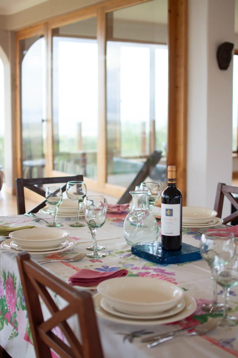 La Maison Bleue Naivasha — dining table set for a group beside wraparound windows