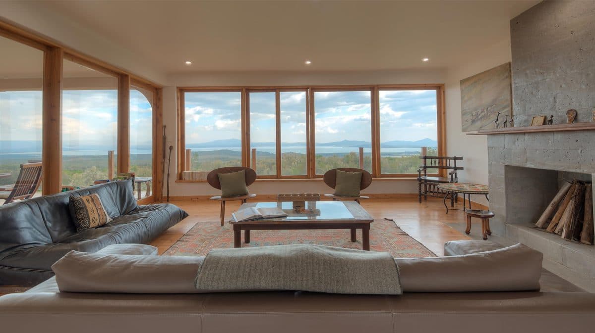 La Maison Bleue Naivasha — living room at dusk with stone fireplace and open valley windows