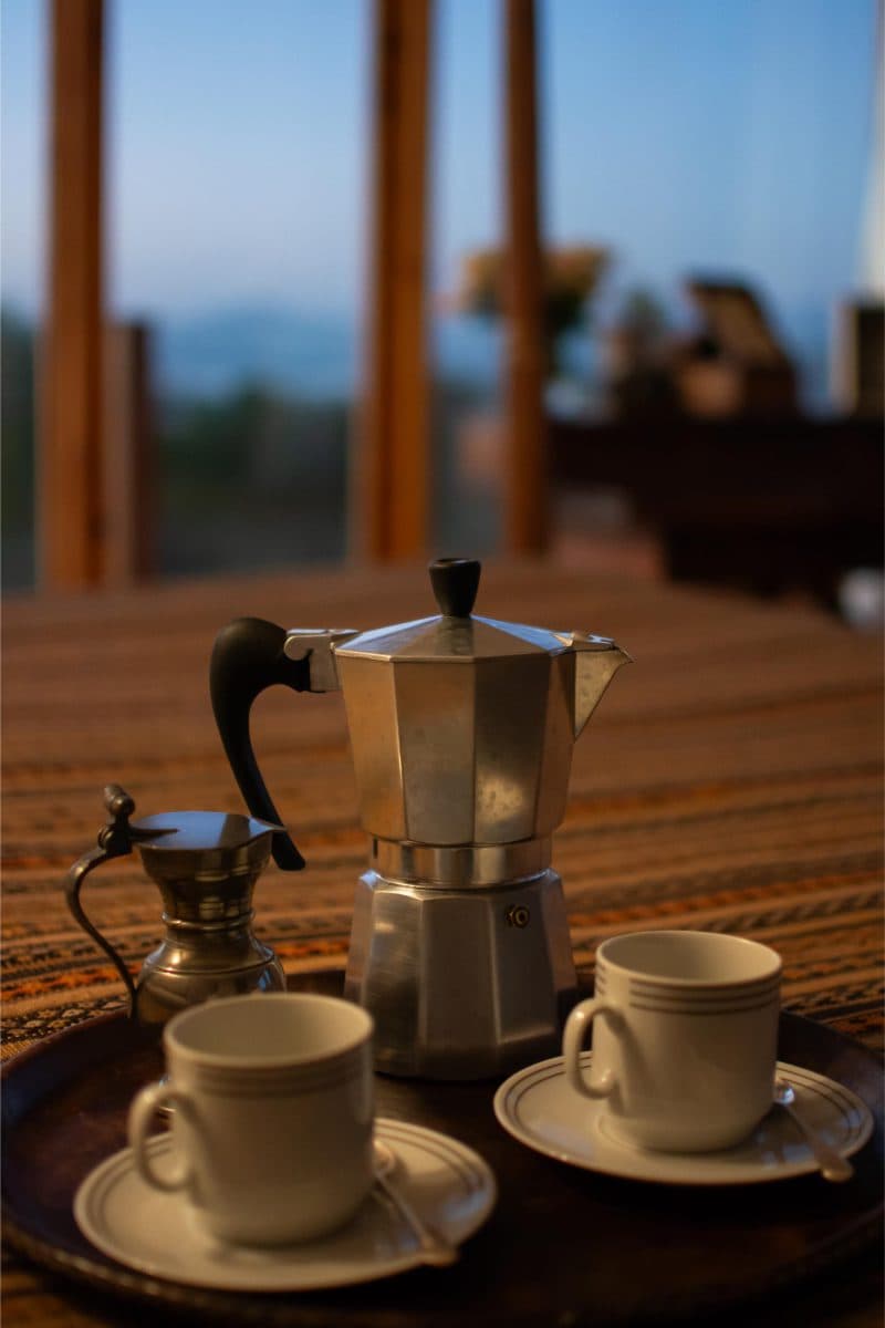 La Maison Bleue Naivasha — coffee tray on the bedspread with twilight hills beyond