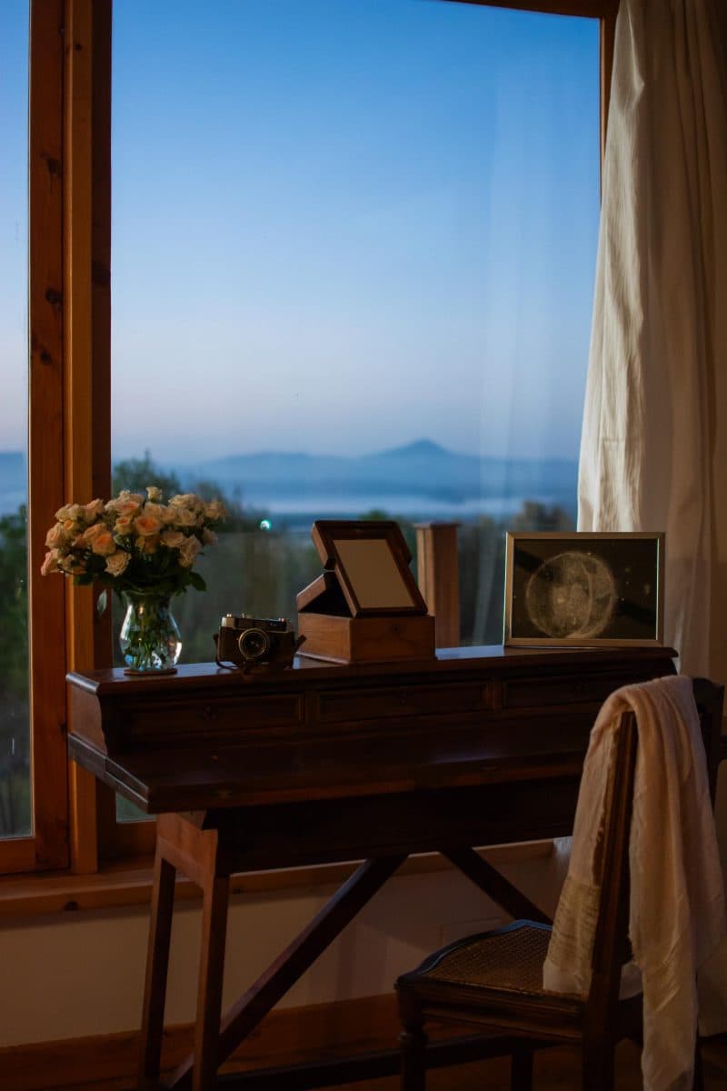 La Maison Bleue Naivasha — wooden writing desk and chair by a dusk landscape window