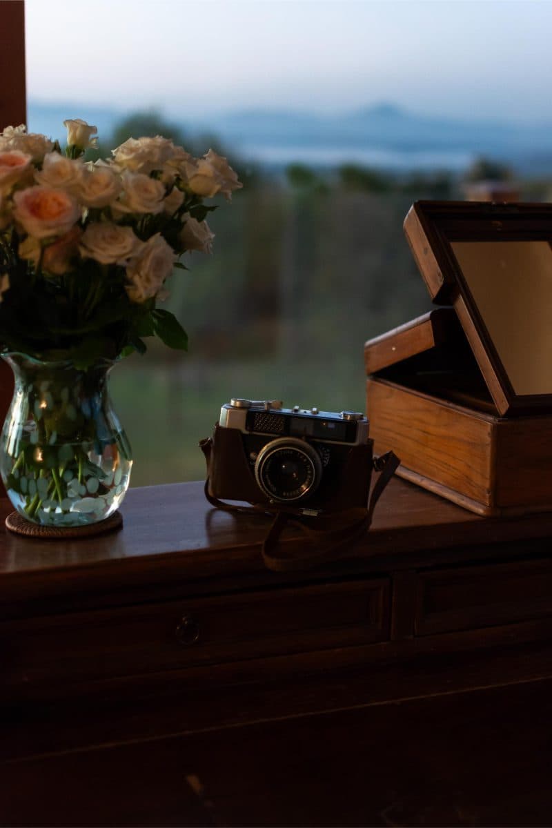 La Maison Bleue Naivasha — cream roses and a vintage camera on the bedroom desk