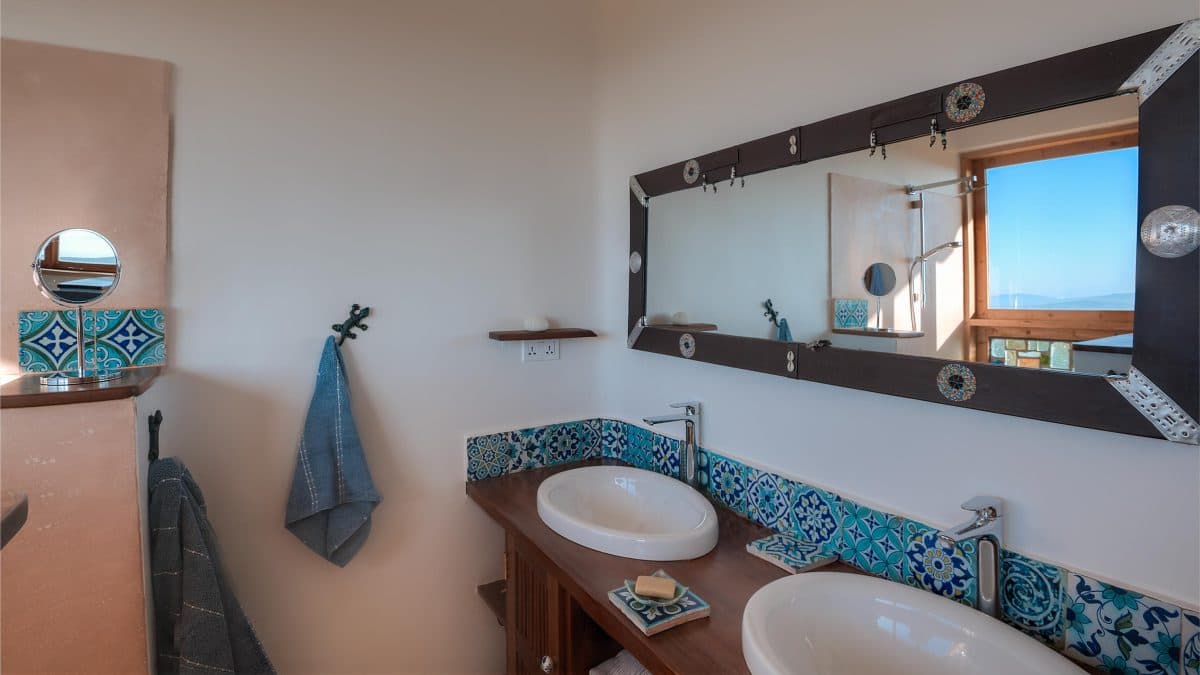 La Maison Bleue Naivasha — double vanity with studded mirror and blue tile backsplash