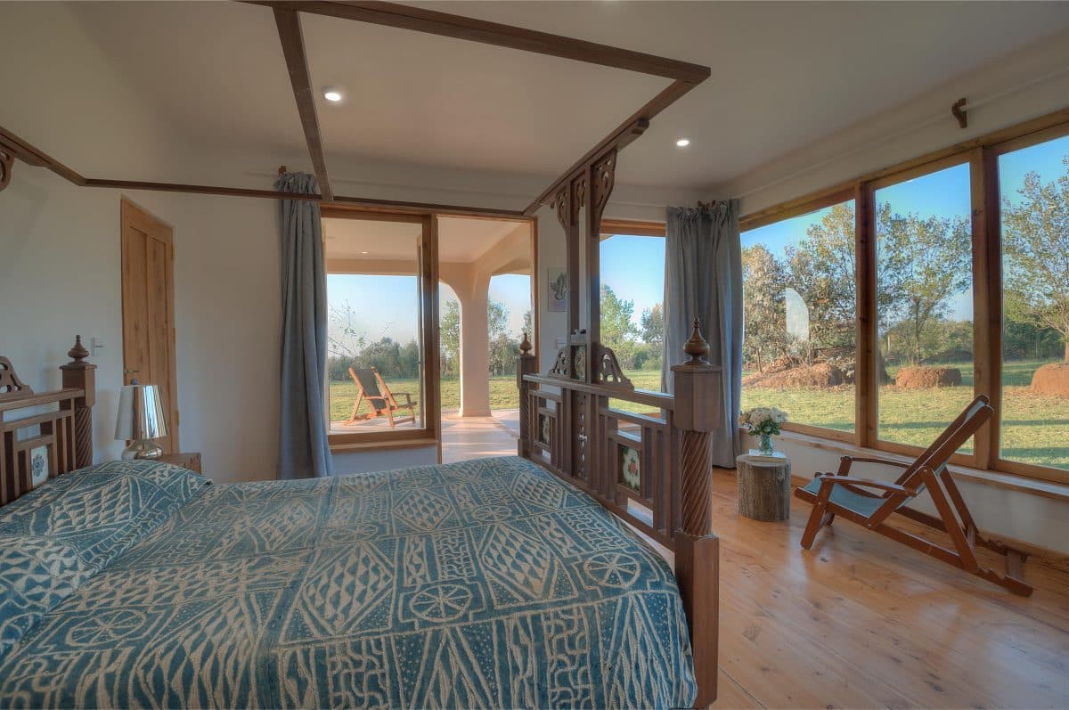 La Maison Bleue Naivasha — four-poster bedroom with blue bedding opening to the lawn