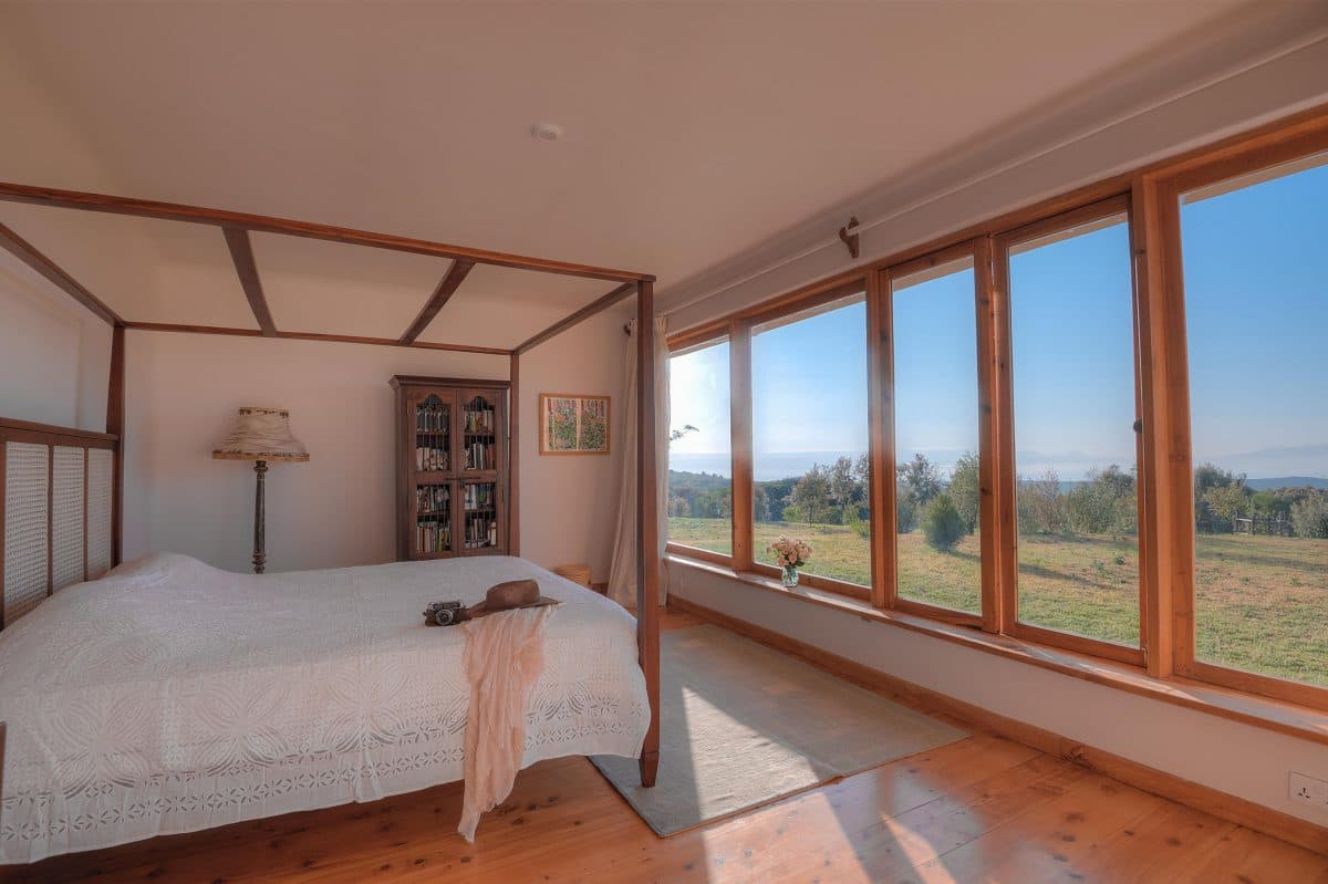La Maison Bleue Naivasha — four-poster bed with white linens and hillside windows